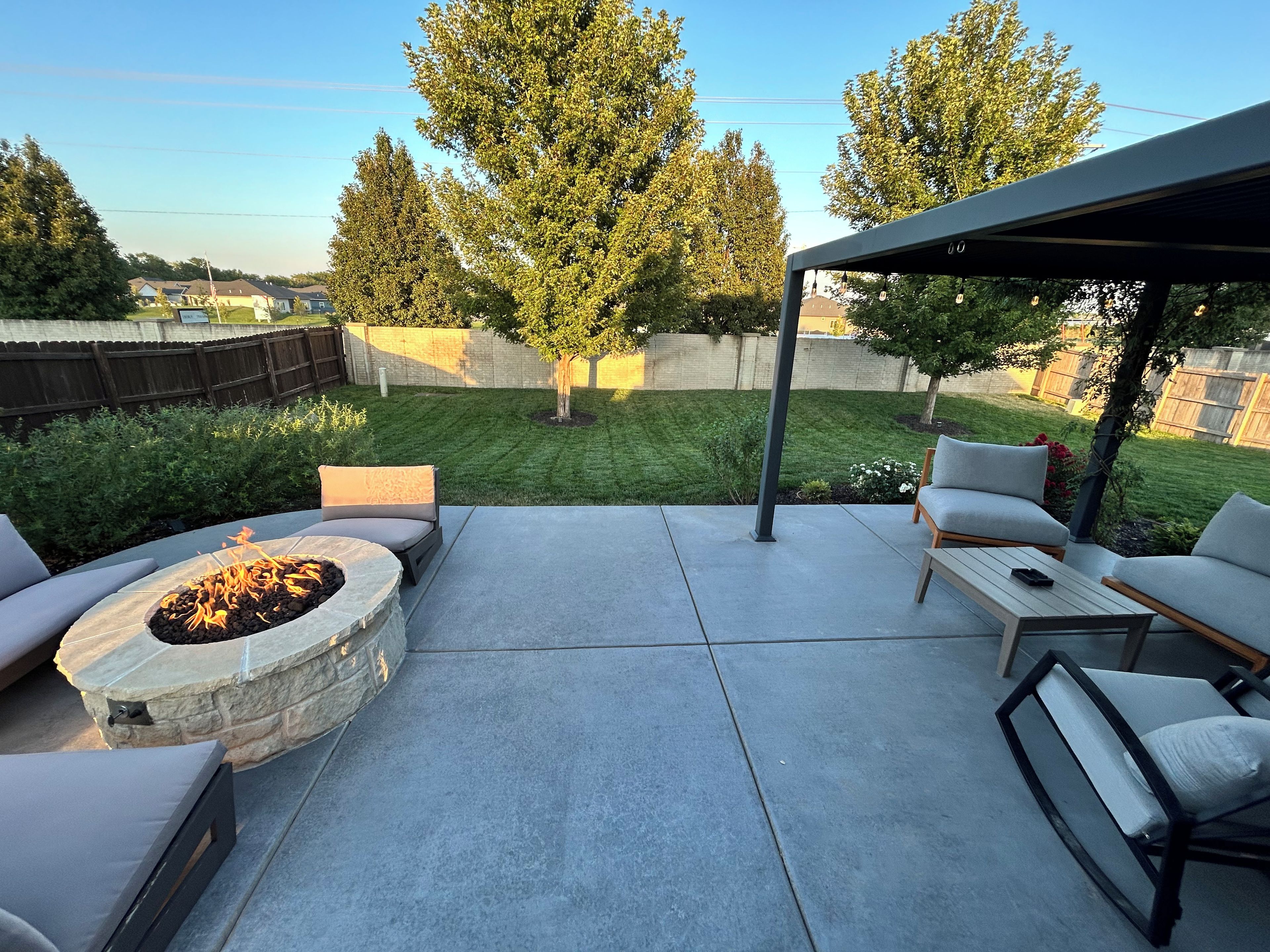 A patio with a stone fire pit, outdoor furniture, and a covered seating area.