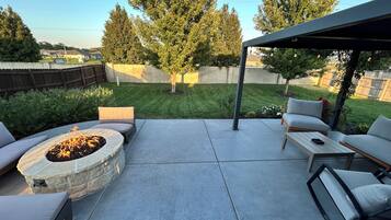 A patio with a stone fire pit, outdoor furniture, and a covered seating area.