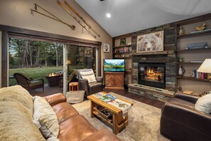 A cozy living room with a fireplace, comfortable seating, and a television. - Chickadee Cabin | Cozy WF Retreat mins to Downtown (Whitefish)