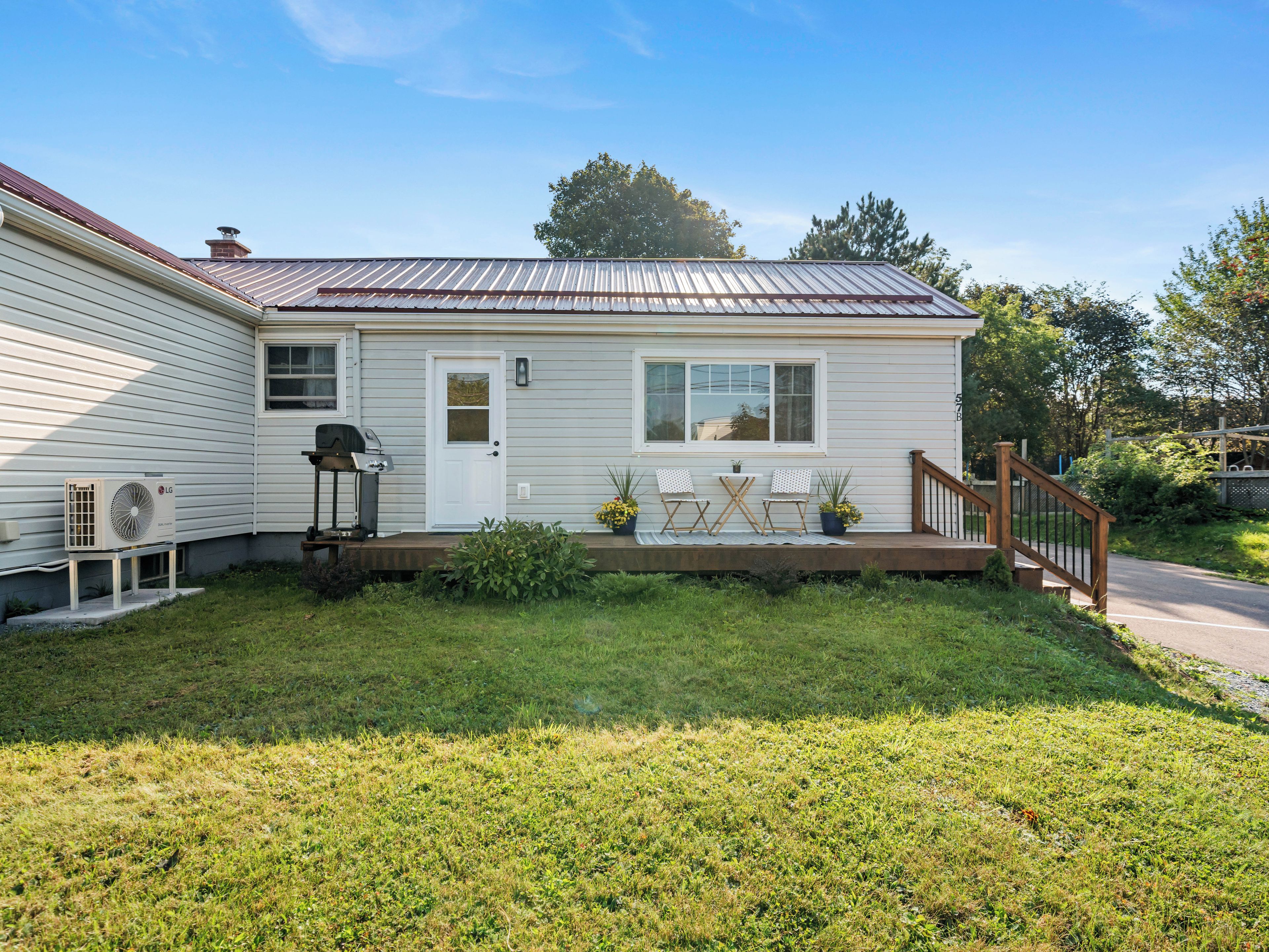 A single-story house with a front porch, a grill, and a small garden area.