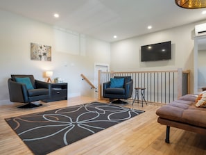 A modern living room with two sofas, a coffee table, a TV, and a staircase.