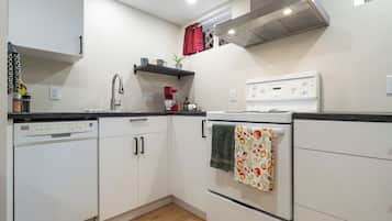 A compact kitchen with white cabinets, a dishwasher, a stove, and a sink.
