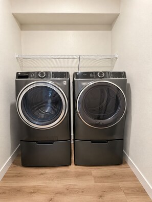 Twee voorladers wasmachines in een wasserette met een houten vloer en een witte muur.