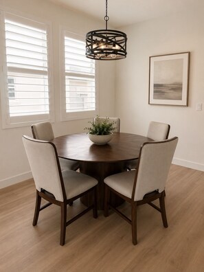 A dining area with a round table, four chairs, a central plant, and a hanging light fixture. - Spacious 2-bedroom + office/gym townhome in charming Summerlin (Las Vegas)