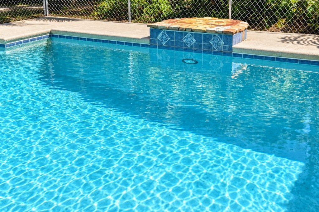 A clear swimming pool with a tiled edge and a stone ledge.