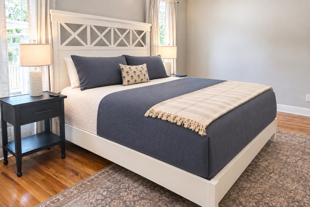 A bed with a headboard, two bedside tables, and a patterned rug.