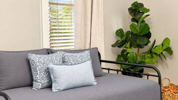 A grey sofa with patterned pillows, a potted plant, and a woven basket.