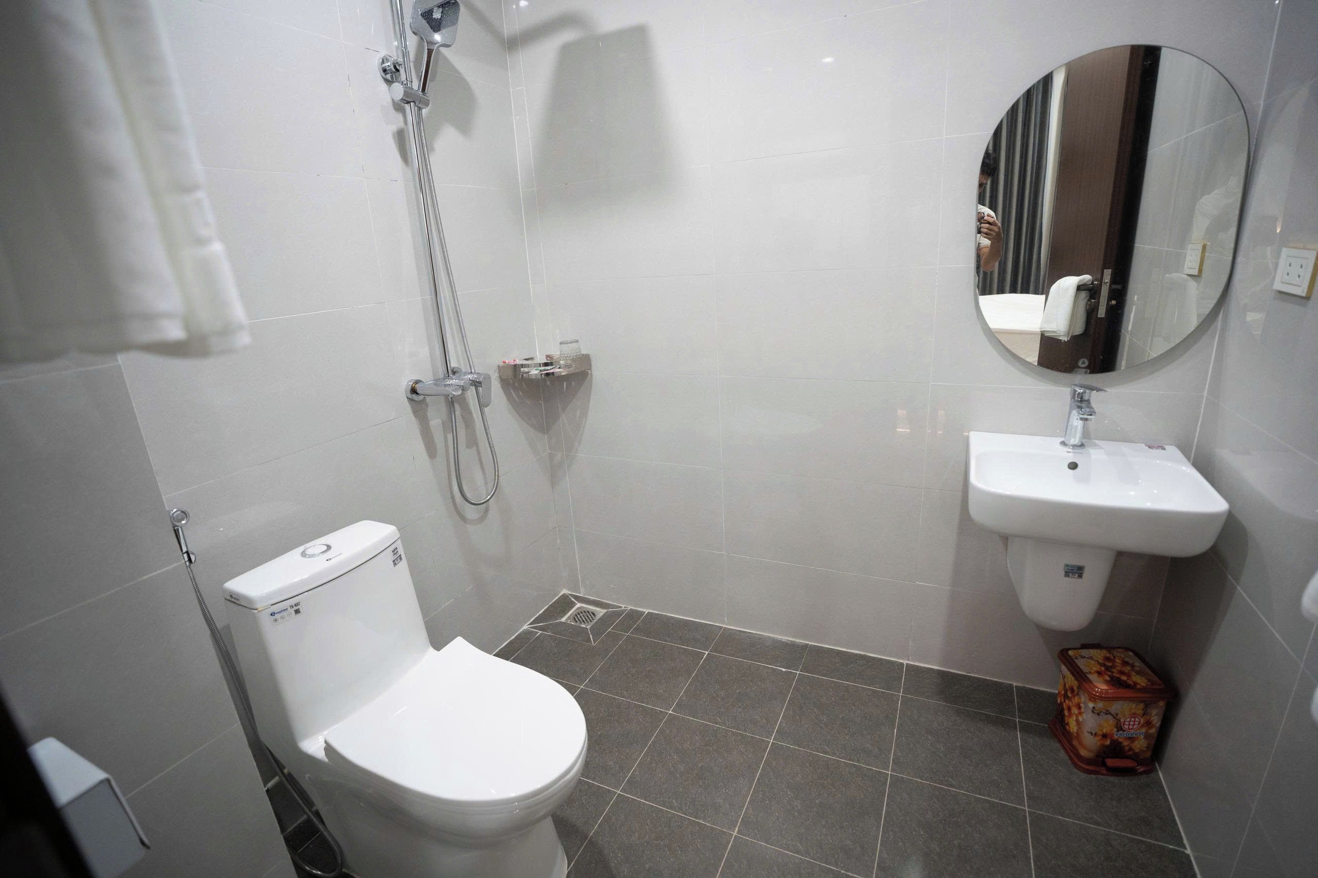 A bathroom with a toilet, a shower, and a sink.
