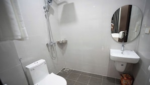 Et badeværelse med toilet, bruser og håndvask.