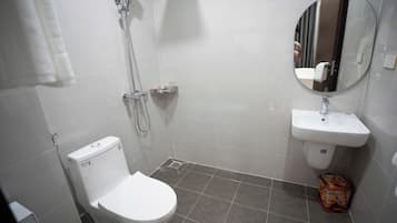 A bathroom with a toilet, a shower, and a sink.