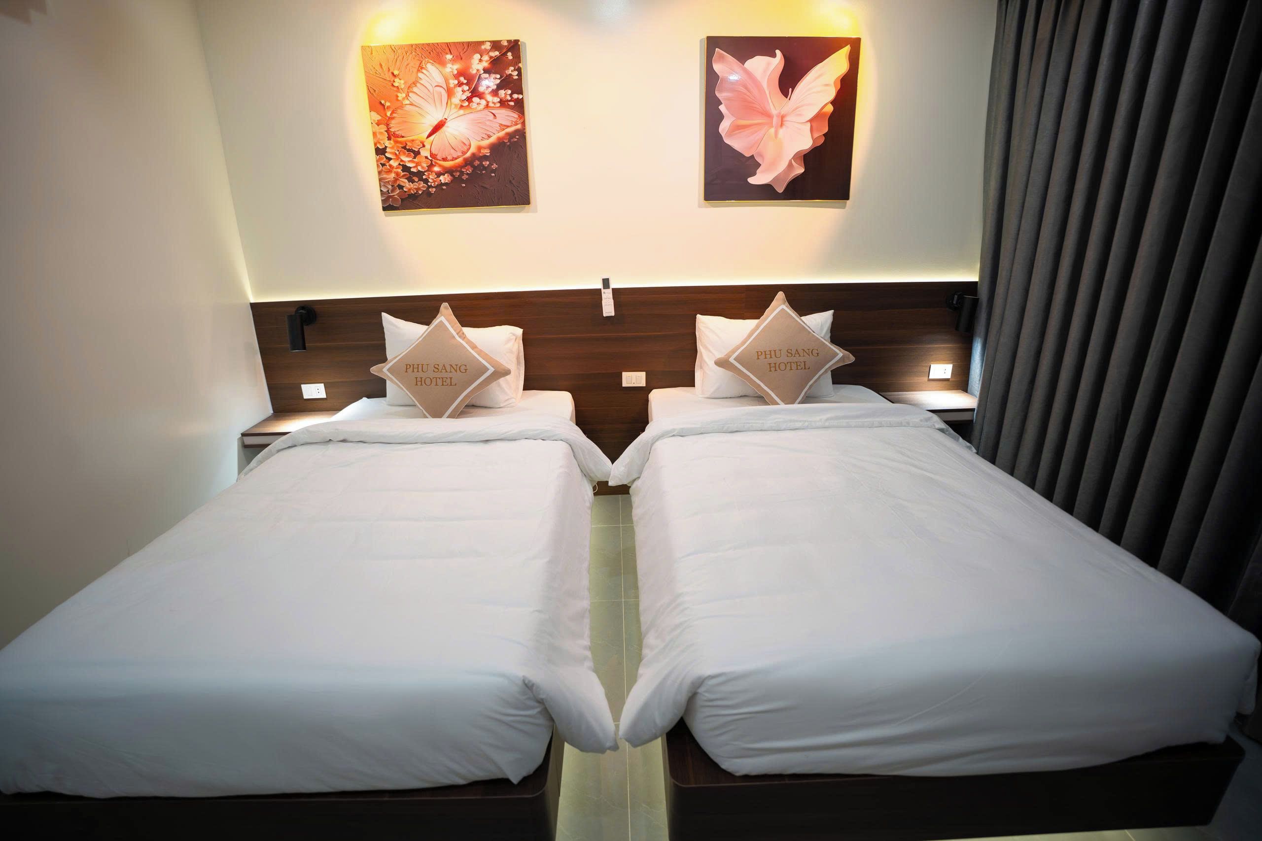 A hotel room with two beds, each with a pillow displaying the hotel name.