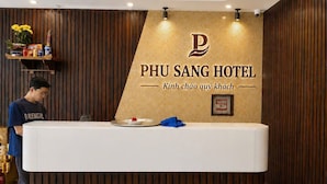 En receptionsdisk på PHU SANG HOTEL med en træpanelvæg og et logo.