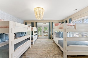 A room with bunk beds, a patterned rug, and a chandelier. - Beach Retreat-Sleeps 22-Outdoor Oasis-Golf Sim-Gym (North Myrtle Beach)