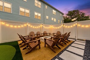 A backyard with a wooden deck, outdoor furniture, and string lights. - Beach Retreat-Sleeps 22-Outdoor Oasis-Golf Sim-Gym (North Myrtle Beach)