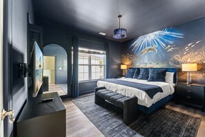 Une chambre moderne avec un grand lit, un téléviseur et une fresque murale représentant la vie marine.