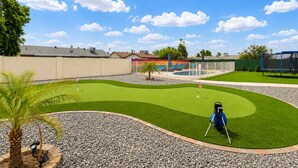 Un parcours de golf comprenant un green d’entraînement, un bunker de sable et un obstacle d’eau.