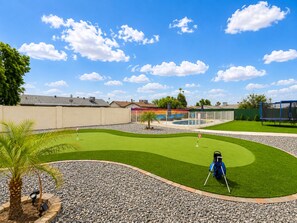 Een golfbaan met een putting green, een zandbunker en een waterhindernis.