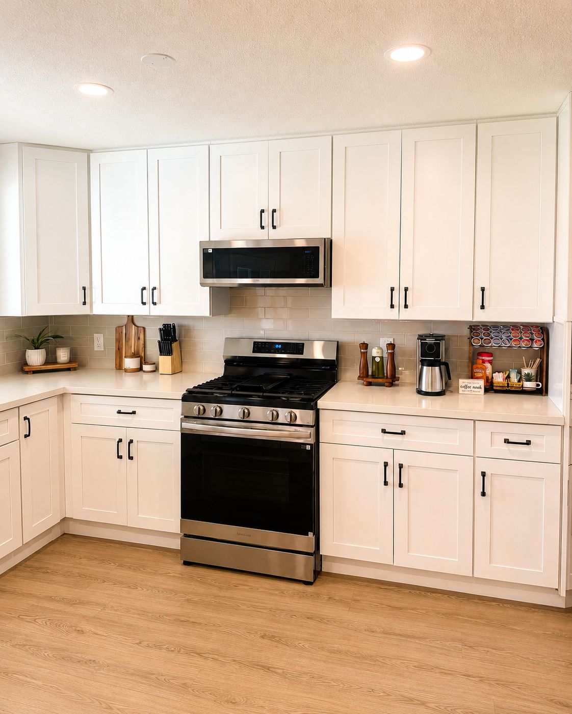 A kitchen with white cabinets, a stainless steel stove, a microwave, and a coffee maker.