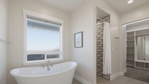 A bathroom with a freestanding bathtub, a window with frosted glass, and a walk-in closet with shelves. - Spacious High End Ranch near Lake Lowell (Nampa)