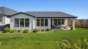 A single-story house with a covered patio, a lawn, and a wooden fence in the background. - Spacious High End Ranch near Lake Lowell (Nampa)