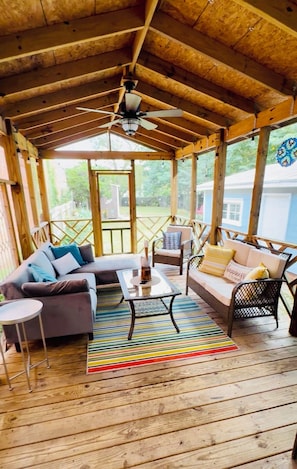 A covered outdoor seating area with wooden flooring, a ceiling fan, and a view of a blue house in the background. - Historic charm meets contemporary style-steps away from downtown and waterfront (Washington)