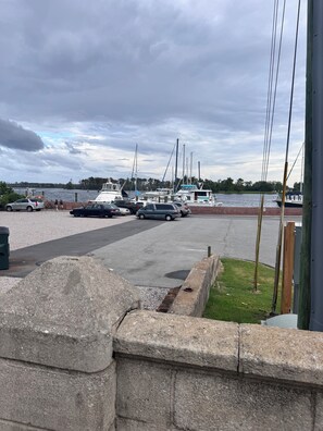 A marina with boats docked, a parking area with cars, and a grassy area with a wooden fence. - Historic charm meets contemporary style-steps away from downtown and waterfront (Washington)