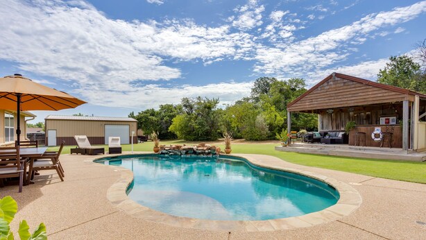 Piscina com cachoeira artificial integrada, rodeada por um espaço de lazer com espreguiçadeiras e área coberta para churrasco.