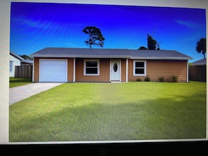 Une maison d’habitation avec un garage, une porte d’entrée et un petit jardin devant.