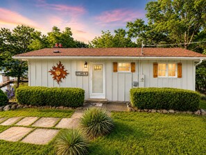 A single-story house with a white facade, a red-tiled roof, and a front door with a small window above it. - Lakefront Getaway With Dock Near Bagnell Dam & Dining (Sunrise Beach)