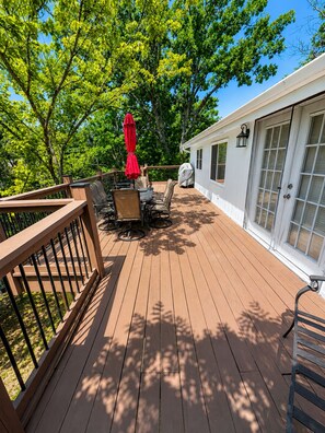 A wooden deck with outdoor furniture, a covered table, and a red umbrella. - Lakefront Getaway With Dock Near Bagnell Dam & Dining (Sunrise Beach)