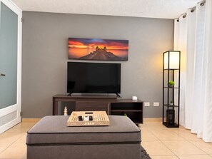 A modern living room with a flat-screen TV, a wooden entertainment unit, and a cozy seating area. - Ventana Azul Direct Beach Access Condo (Cabo Rojo)