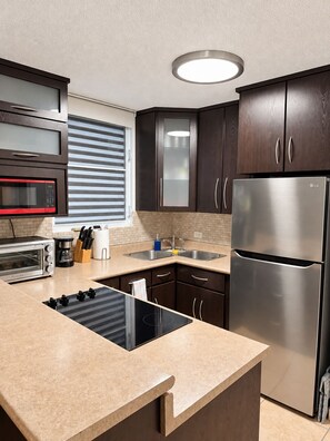 A modern kitchen with a built-in oven, microwave, toaster, and stainless steel refrigerator. - Ventana Azul Direct Beach Access Condo (Cabo Rojo)