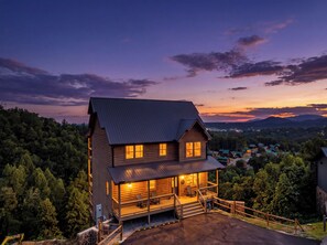 Eine zweistöckige Holzhütte mit Veranda und Blick auf den umliegenden Wald.