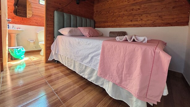 A wooden room with a bed, a window, and a bathroom visible through an open door. - Alegria Stay Glamping in Cocorná (Cocorná)