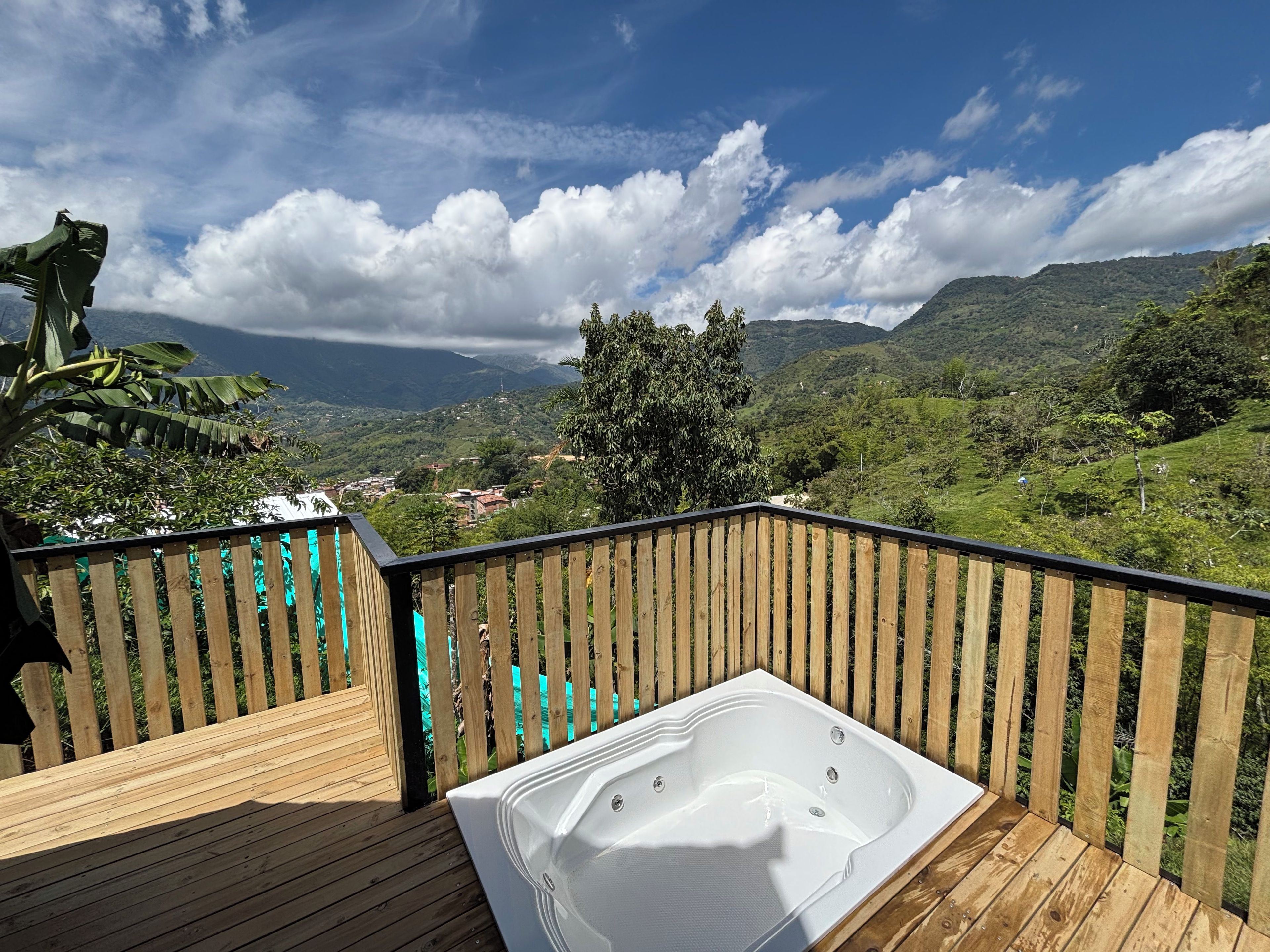 Eine Holzterrasse mit Whirlpool und Blick auf eine gebirgige Landschaft.