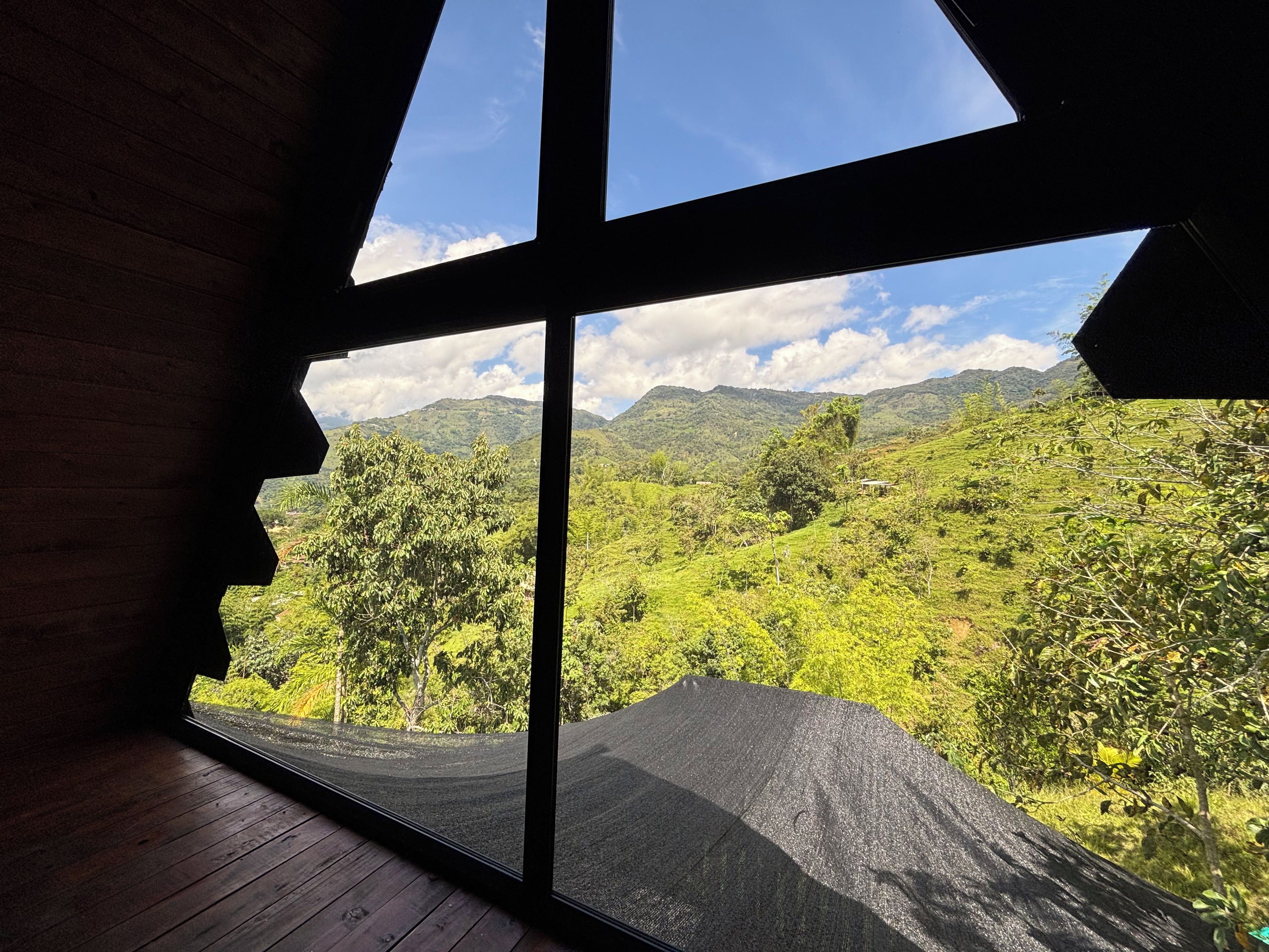 Ein Zimmer mit einem großen Fenster mit Blick auf eine üppige grüne Landschaft und Berge in der Ferne.