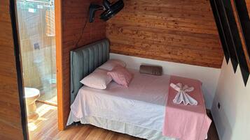 Ein Schlafzimmer mit Holzboden, einem Bett mit rosa Bettwäsche, einem Kopfteil und einem Handtuch auf dem Bett.