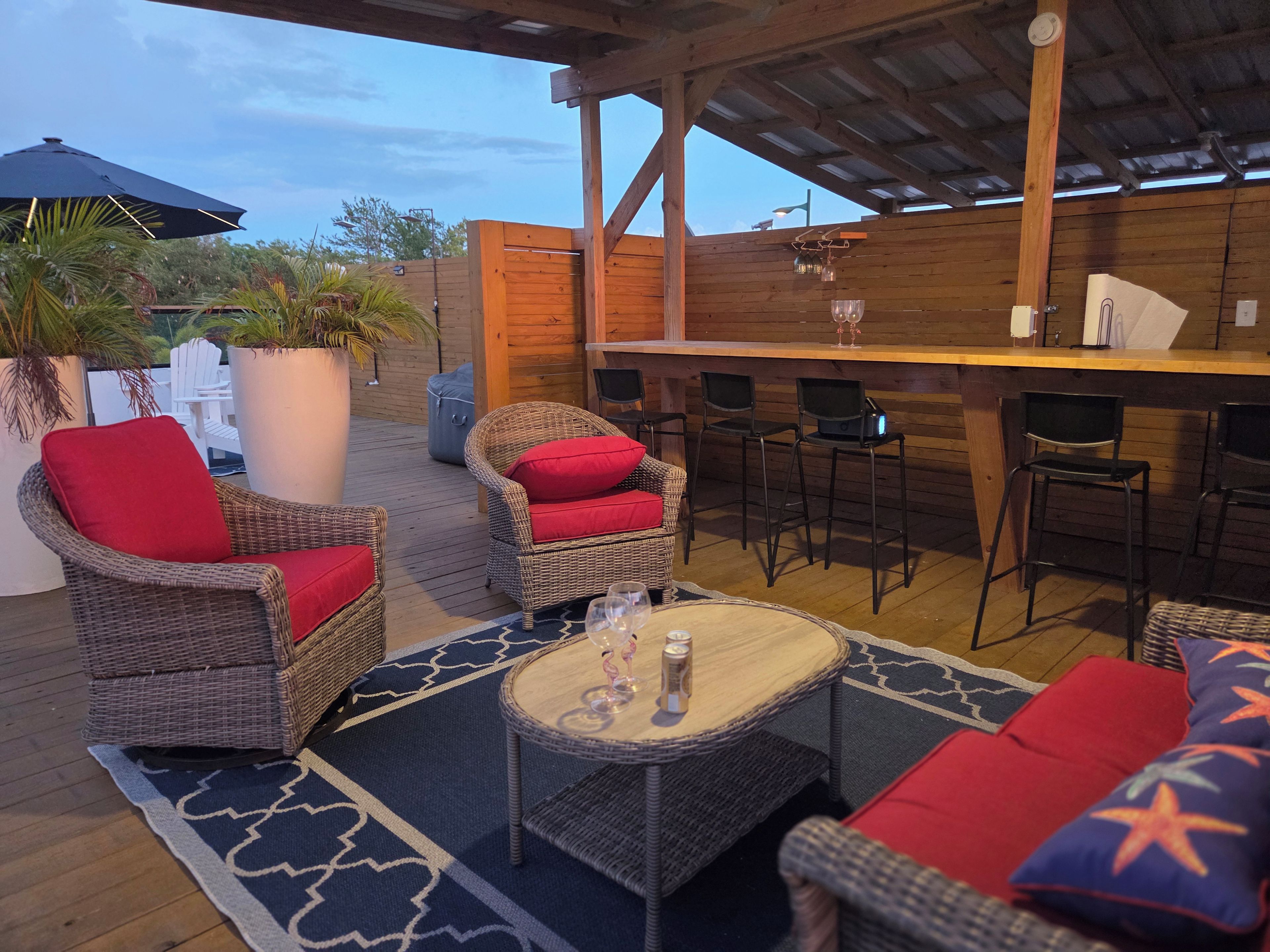 Un patio exterior con mobiliario de mimbre, una zona de bar y vistas al cielo.