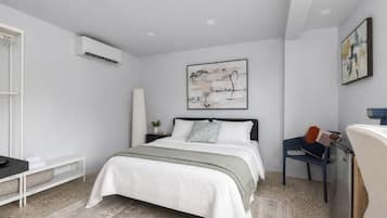 Un dormitorio moderno con cama, mesita de noche y escritorio con silla.