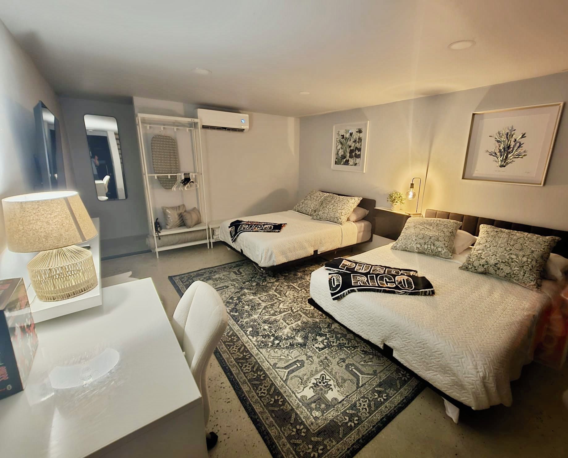 A hotel room with two beds, a desk, a chair, a wardrobe, and a rug.