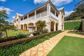 A large, two-story building with a covered balcony area and a central courtyard with a fountain.