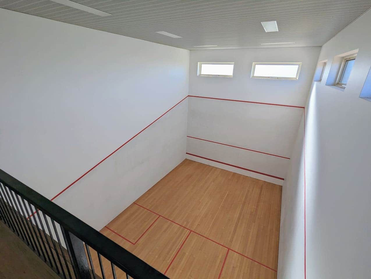A room with white walls, a wooden floor, and red lines marking the space.
