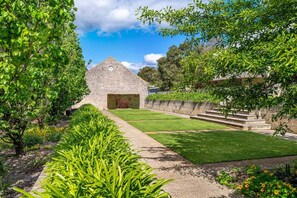 A stone building with a triangular roof, surrounded by well-maintained lawns and trees.