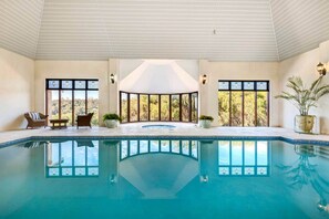 Una grande piscina interna con vista su alberi attraverso ampie finestre.