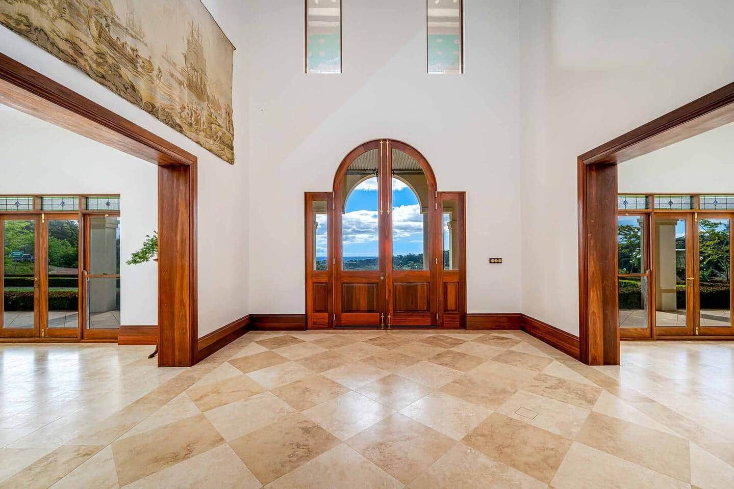 Un intérieur spacieux avec une grande porte en arc, un plafond haut et une vue dégagée à travers les portes.
