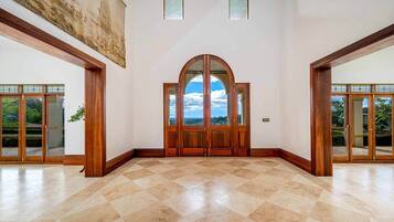 Un intérieur spacieux avec une grande porte en arc, un plafond haut et une vue dégagée à travers les portes.