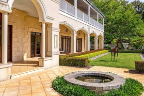 A building with a covered outdoor area, a circular water feature, and a giraffe statue.