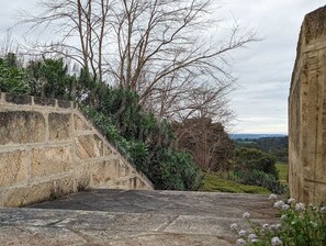 A stone staircase leading down a hill with a view of trees and a distant landscape.