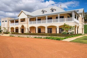 A two-story building with a balcony, arched windows, and a stone facade.