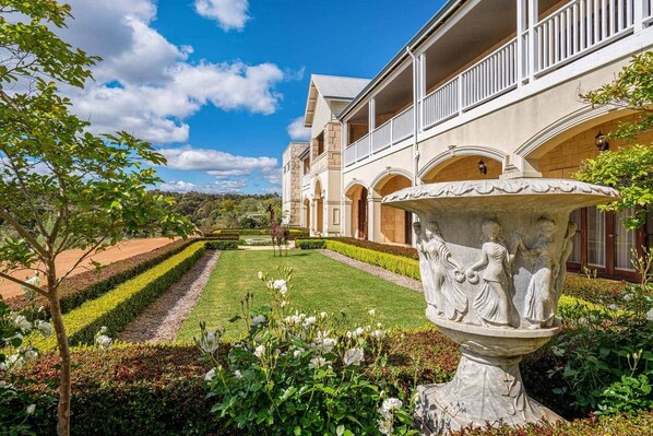 A building with a garden, a fountain, and a giraffe statue.